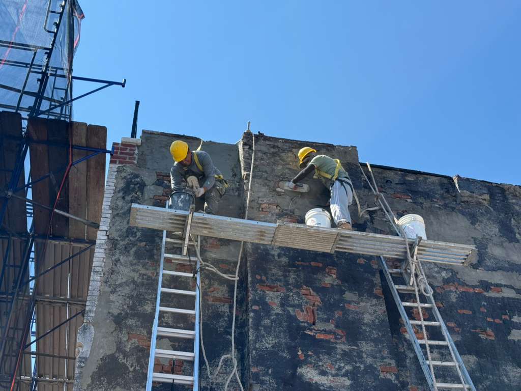 ECO World crew on ladder jacks cutting back and repairing deteriorated brick on an exterior wall